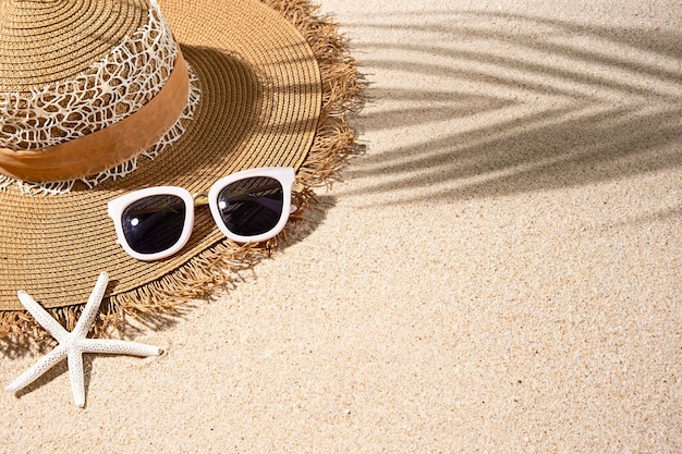 Calor de verano redondo marrón grande, gafas de sol blancas y estrellas de mar en la arena de la playa, vista superior, espacio de copia