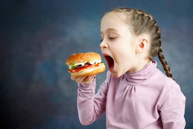 Foto calorías americanas comida gorda comida chatarra, niña disfruta comiendo hamburguesas hamburguesa de comida rápida poco saludable