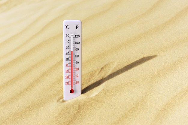 Foto caluroso día de verano termómetro de escala celsius y fahrenheit en la arena temperatura ambiente más 26