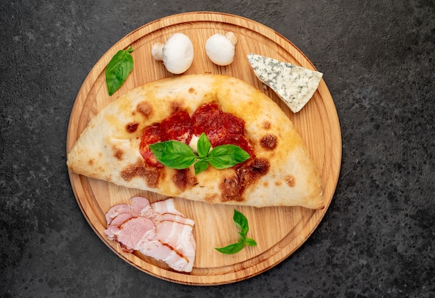 Calzone con jamón y setas sobre un fondo de piedra