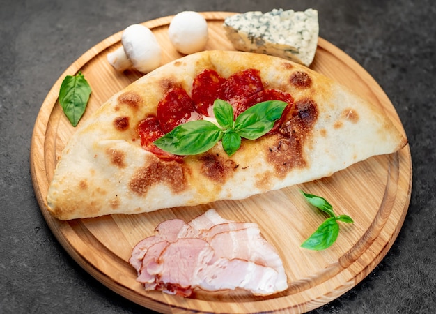 Calzone con jamón y setas sobre un fondo de piedra