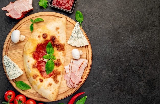 Calzone mit Schinken und Pilzen auf Steinhintergrund mit Kopienraum für Ihren Text