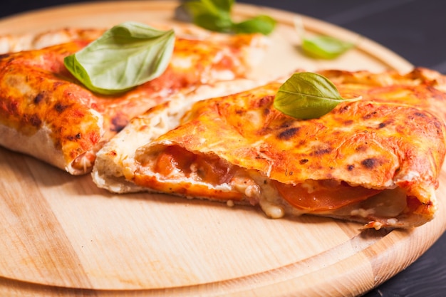 Calzone de pizza con hojas de albahaca cerrar