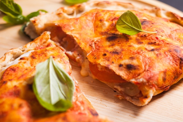 Calzone de pizza con hojas de albahaca cerrar