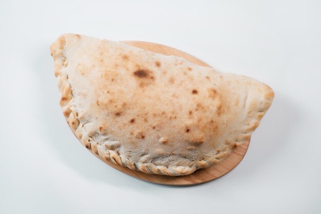 Calzone de pizza italiana sobre una tabla de madera Pastel italiano en forma cerrada de pizza hecha en forma de media luna Entrega de comida rápida italiana