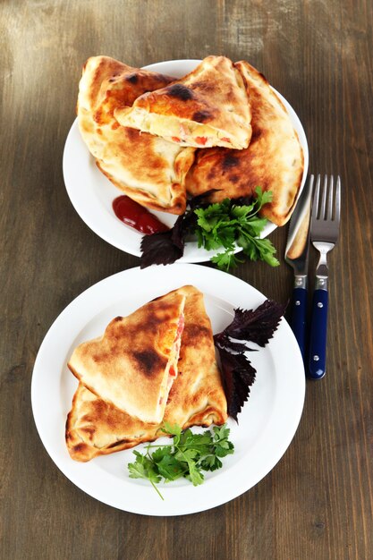 Calzones de pizza em pratos na mesa de madeira