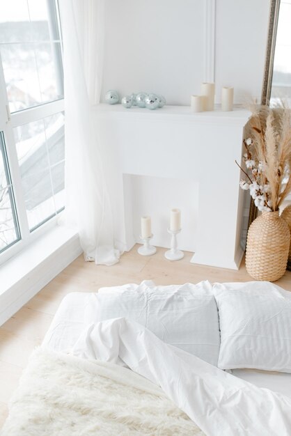 Una cama blanca y una chimenea decorativa blanca Dormitorio acogedor y luminoso en estilo minimalista Minimalista