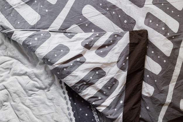 La cama casera abstracta en blanco y negro textil con mantas y sábanas