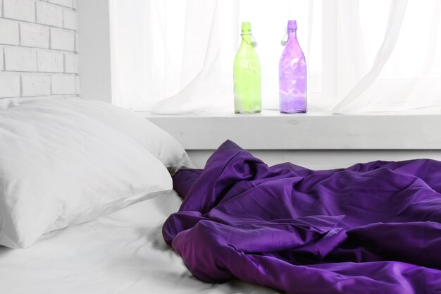 Cama confortável com cobertor roxo e travesseiros no quarto