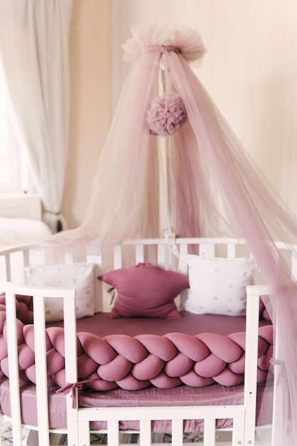 Foto cama de dossel rosa bebê com pompons e almofadas