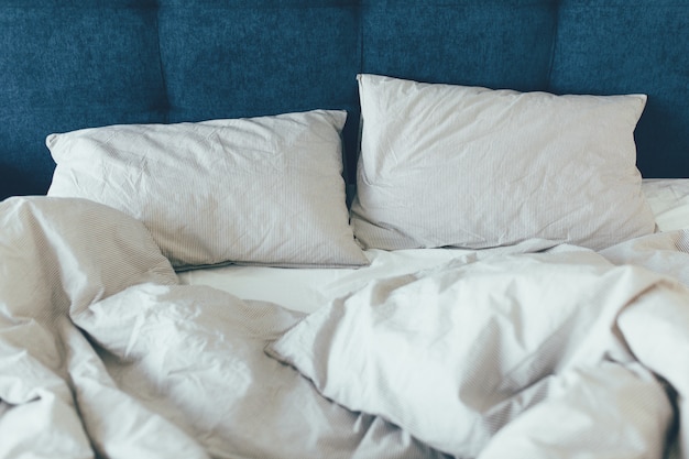 Cama de empregada com almofadas brancas limpas e lençóis na sala de beleza. Fechar-se.