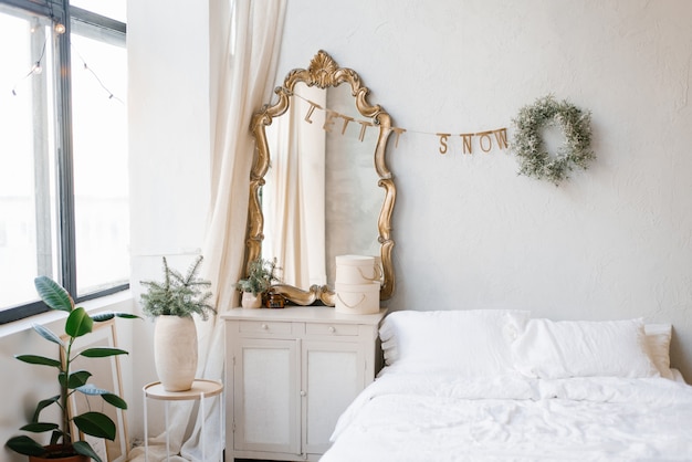 Una cama doble con sábanas y almohadas blancas en el dormitorio decorado para Navidad