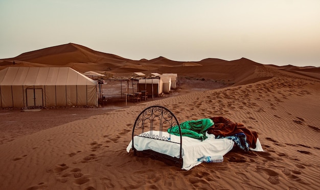 Foto cama en una duna de arena en el desierto contra el cielo