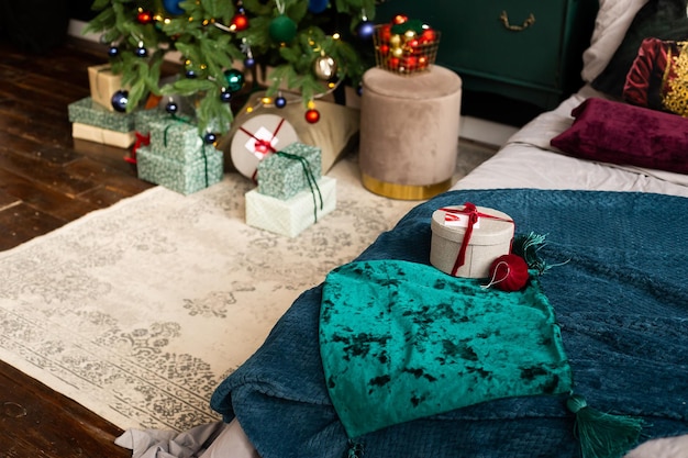 Foto cama em casa com cobertura verde e com presente de caixa de presente de natal e árvore de natal no fundo