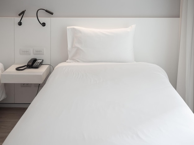 Cama limpa branca com travesseiro branco no quarto do hotel