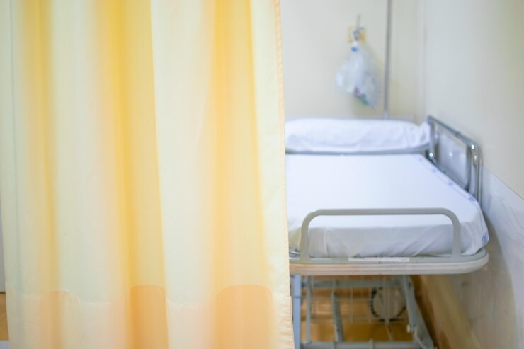 Cama o camilla de hospital con cortina amarilla clara como espacio para copiar