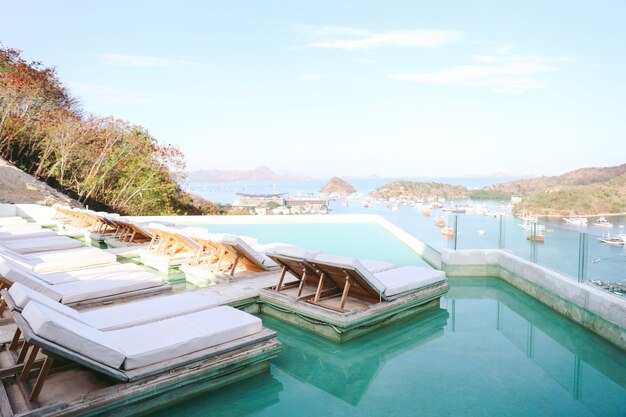 Cama o silla relajante sobre la piscina infinita con vista al mar y al puerto