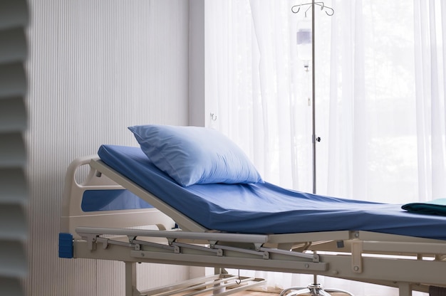 Foto cama vacía limpia y limpia en la habitación del hospital para el paciente de apoyo