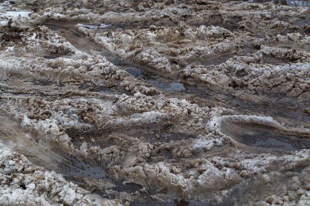 Foto camada de neve molhada suja grossa com trilhas de roda de carro no fundo de quadro completo da rua de inverno