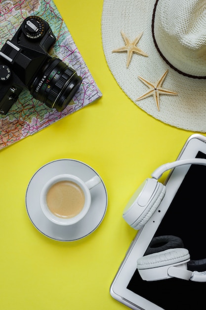 Cámara de accesorios de viaje, sombrero de paja, tarjeta, zapatos en un diseño de vista superior plana de fondo amarillo con espacio de copia