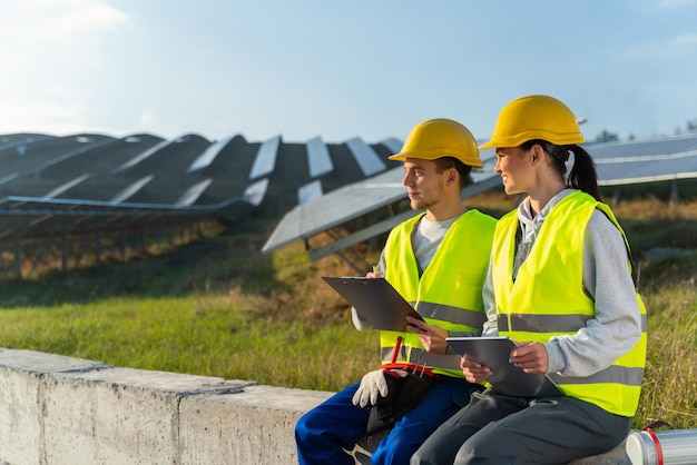 La cámara se acerca a dos técnicos solares agrícolas Una mujer y un hombre miran hacia otro lado atentamente mientras trabajan con una tableta electrónica Concepto de equipo experimentado