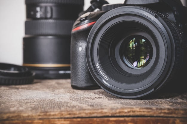 Cámara DSLR negra con lente de primera calidad de 50 mm y 1.8G sobre una superficie de caja vintage de madera marrón