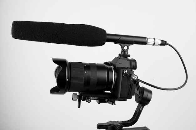 cámara sin espejo y un micrófono conectado montado en un estabilizador electrónico en un backgrou blanco