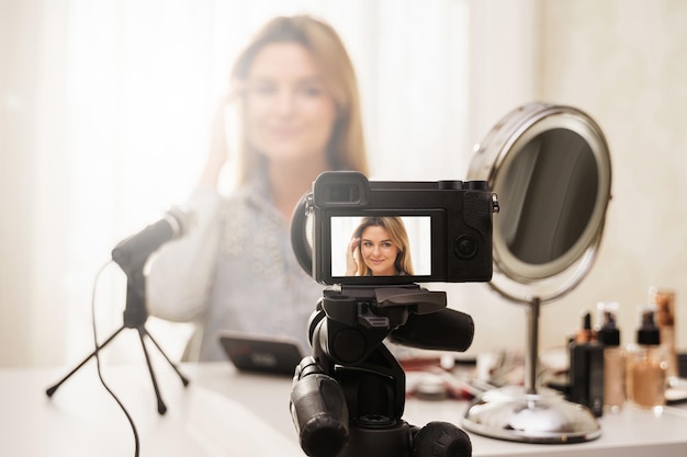 Cámara sin espejo moderna que graba video de la rutina de maquillaje de una bloguera de belleza