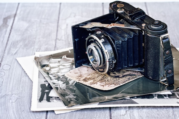 Cámara de fotos antigua con pila de fotos antiguas en la mesa de madera