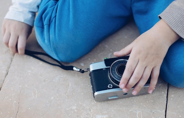 Cámara de fotos de película analógica vintage en mano de un pequeño fotógrafo infantil