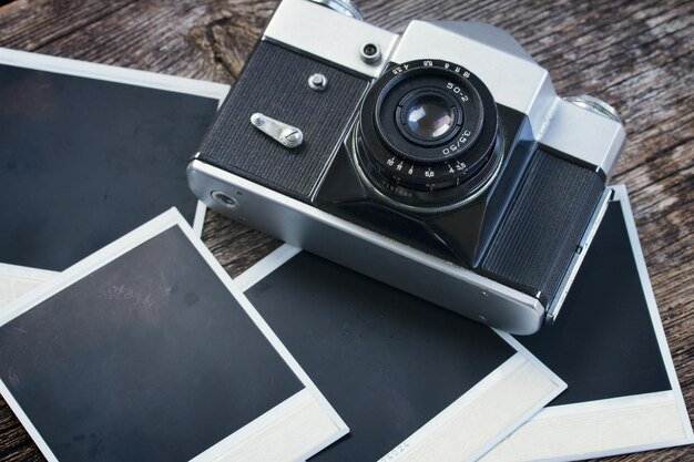 Cámara de fotos vintage en una pila de viejas fotos instantáneas en una mesa de madera con tonos retro