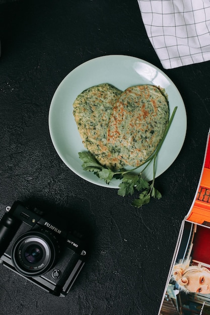 Una cámara junto a un plato de comida con comida en forma de corazón.