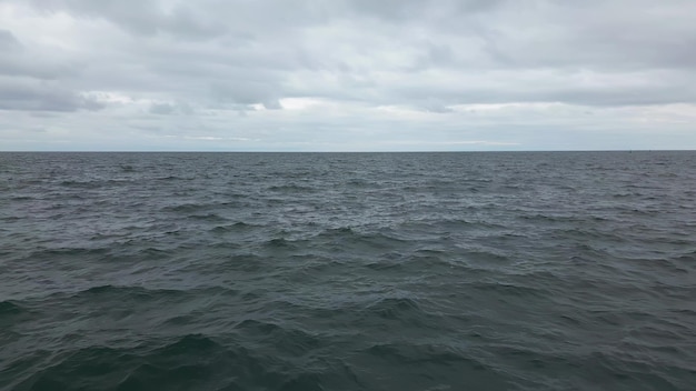 Cámara lenta de superficie de agua de mar perturbada con cielo dramático