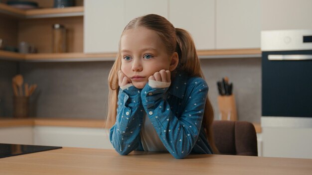 Cámara en movimiento triste niña caucásica ofendida en la cocina aburrida estresada necesita ayuda de los padres