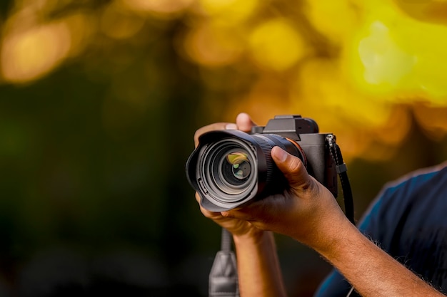 Cámara negra sostenida por la mano del fotógrafo con puesta de sol