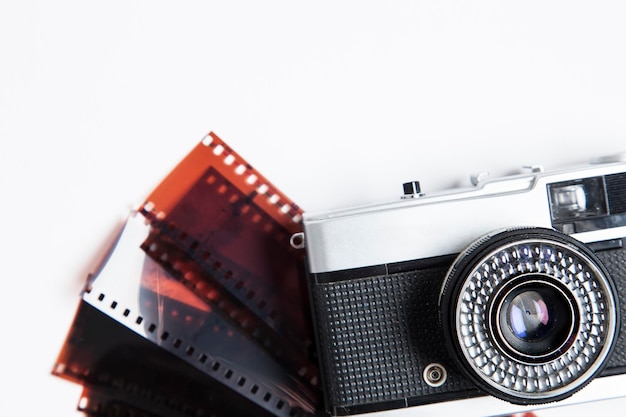 Foto cámara de película vintage y negativos sobre un fondo blanco.