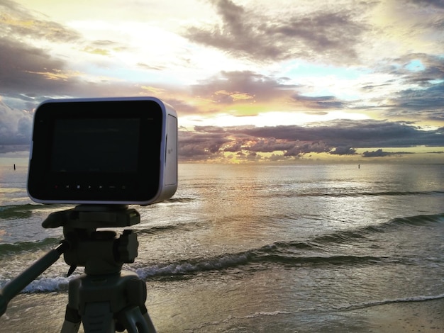 Cámara en la playa contra el cielo durante la puesta de sol