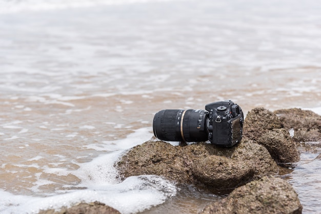 Cámara réflex digital en la playa mojada de agua mar ola