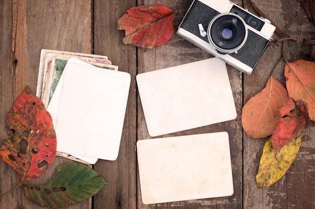 Foto cámara retro y vacío viejo álbum de fotos de papel instantáneo en la mesa de madera con hojas de arce en el diseño de la frontera de otoño - concepto de recuerdo y nostalgia en la temporada de otoño. estilo rústico de la vendimia.