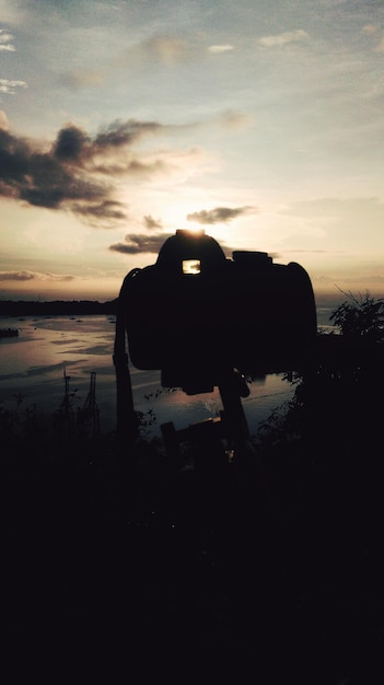 Foto cámara de silueta contra el cielo durante la puesta de sol