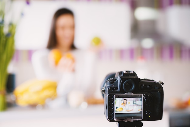 Foto cámara tomando foto de una encantadora joven con frutas.