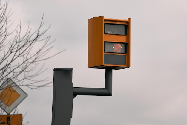 Una cámara de velocidad amarilla parpadea cuando detecta un automóvil que avanza en una autopista utilizando radar e inteligencia artificial para reconocer la matrícula y emitir una multa