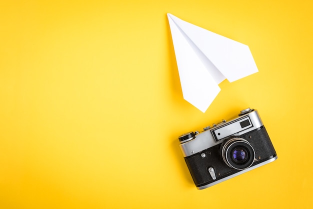 Cámara vieja y avión de papel en amarillo