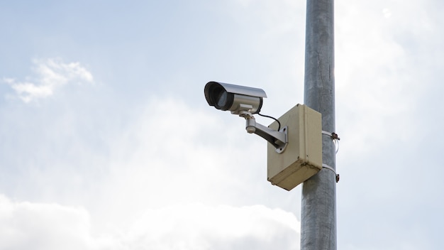 Cámara de vigilancia montada en un poste con fondo de cielo.