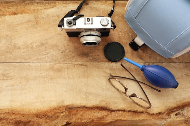 Foto cámara vintage con bolsa y gafas en el tablero de madera