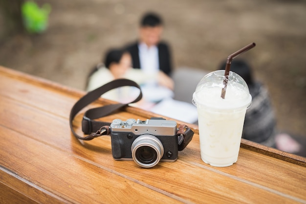 Cámara vintage con café helado en mesa de madera