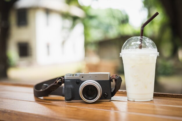 Cámara vintage con café helado en mesa de madera