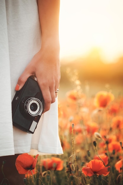 Cámara vintage en mano de mujer en campo de amapolas