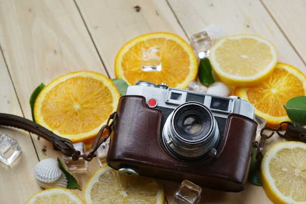 Cámara Vintage entre naranjas frescas Limón conchas de mar hojas cubo de hielo