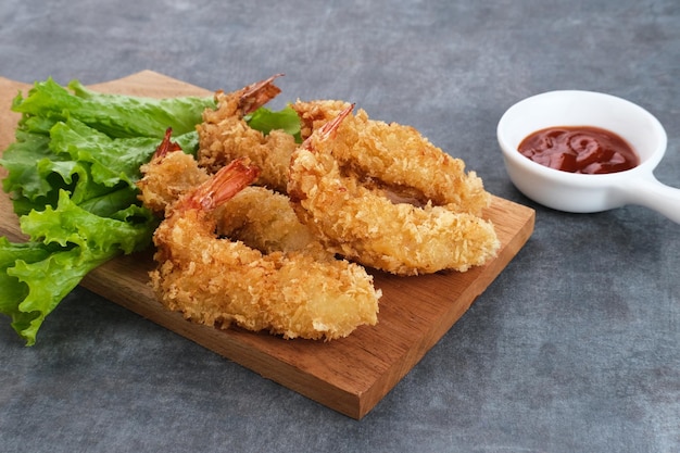 Camarão à milanesa frito com legumes no prato servido com molho de pimenta